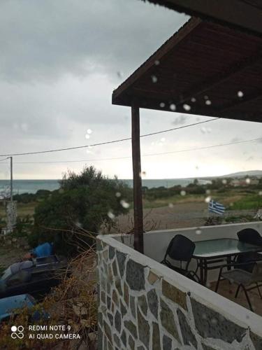 a patio with a table and chairs on a stone wall at To nisaki(το νησακι) in Asklipiḯon