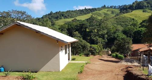 um edifício branco com uma montanha ao fundo em Chalé no campo à caminho de Monte Verde em Camanducaia