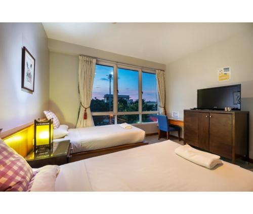 a hotel room with two beds and a flat screen tv at Dinso Home Boutique in Bangkok