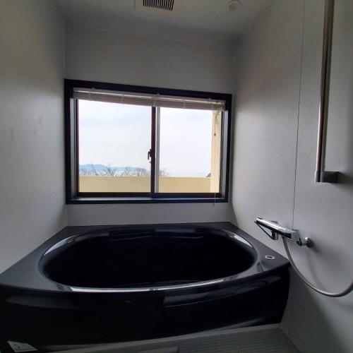 - dużą czarną wannę w łazience z oknem w obiekcie Agri Museum NADA - Vacation STAY 40517v w mieście Minamiawaji
