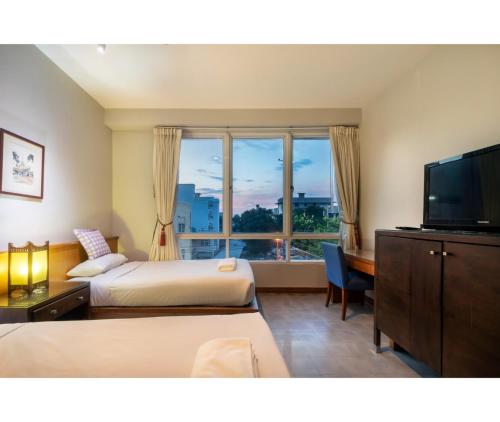 a hotel room with two beds and a flat screen tv at Dinso Home Boutique in Bangkok