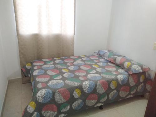 1 dormitorio con cama con colcha de lunares en Arriendo hermoso y amplio apartamento amoblado y con piscina, frente a la estación Niquia y al centro comercial puerta del norte. en Bello