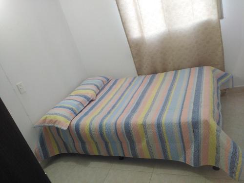 a bed with a striped comforter in a bedroom at Arriendo hermoso y amplio apartamento amoblado y con piscina, frente a la estación Niquia y al centro comercial puerta del norte. in Bello