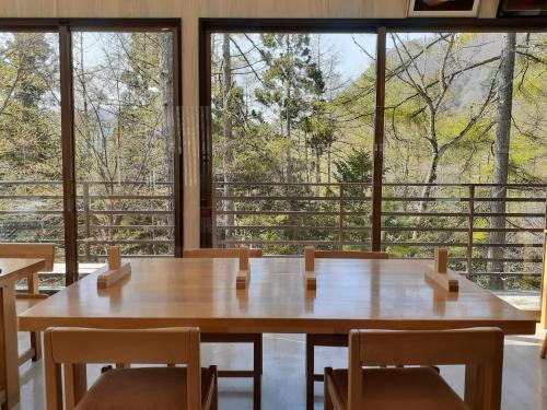 una gran mesa de madera y sillas en una habitación con ventanas en Yasha Gami Hutte - Vacation STAY 36327v, en Minami Alps
