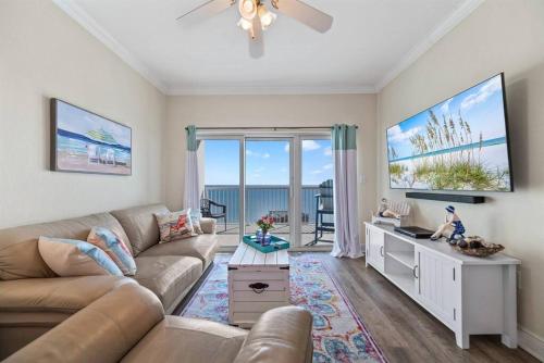 a living room with a couch and a tv at Crystal Tower 1408 - Lazy River, Beachfront pool, Amazing Views, New Upgrades!! in Gulf Shores