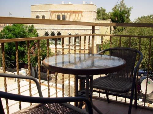 a table and chairs on a balcony with a building at The Little House In Bakah in Jerusalem