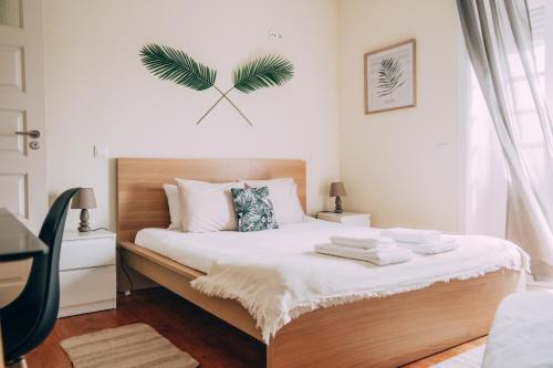 1 dormitorio con 1 cama con una hoja de palmera en la pared en Green Coast Surf House en Espinho