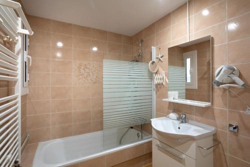 a bathroom with a sink and a bath tub and a mirror at Bonita casa adosada con jardín privado y piscina comunitaria in Calella de Palafrugell