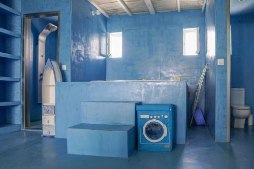 a blue bathroom with a toilet and a blue wall at Boathouse in Kardamaina