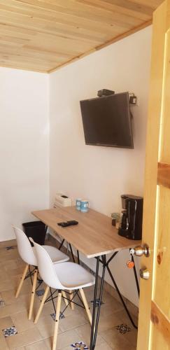 a wooden table with chairs and a television on a wall at Cabaña La Camelia in Creel