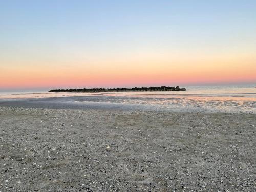 a beach with a pier in the ocean at sunset at La casa di Celeste B&B in Comacchio