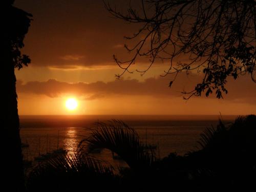 a sunset over the ocean with the sun in the sky at Le matelot de la baie in Deshaies