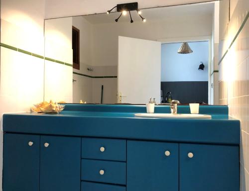 un bagno con un lavandino blu e uno specchio di Le Mayann a Le Diamant