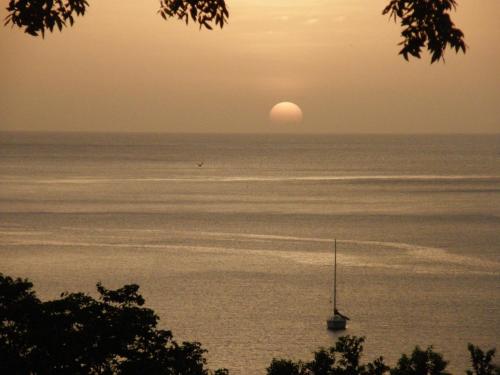 a boat in the water with the sun in the horizon at Le matelot de la baie in Deshaies
