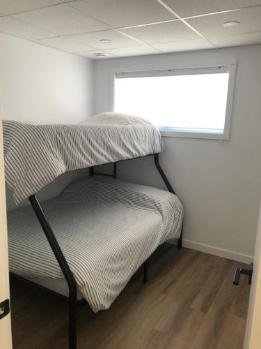 a bunk bed in a room with a window at Chalet Snocamp in LʼAnse-Saint-Jean