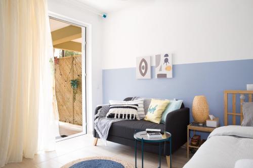 sala de estar con sofá y ventana en Boho Blu by A&D Properties, en Porto Rafti
