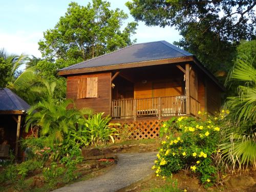 a small wooden cabin with a balcony in a garden at Le matelot de la baie in Deshaies