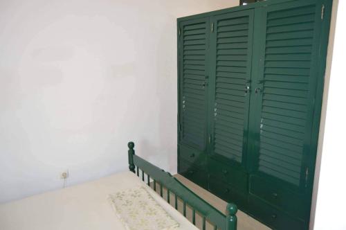 une armoire verte dans une chambre avec un tapis dans l'établissement Apartamento T1 Mobilado com Wi-Fi, à Praia