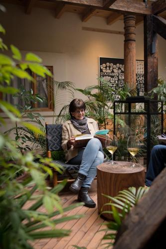 a woman sitting in a chair reading a book at Taller de Juan - Casa Hotel in San Cristóbal de Las Casas