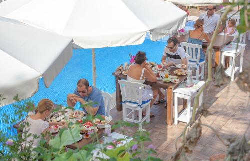 Eine Gruppe von Menschen sitzt an Tischen am Pool und isst. in der Unterkunft Sunset Villa Hotel in Kaş