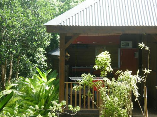 a red house with a porch with a dog in it at Le matelot de la baie in Deshaies