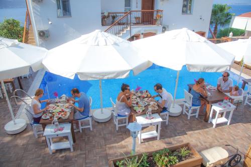 eine Gruppe von Menschen, die an Tischen unter weißen Schirmen sitzen in der Unterkunft Sunset Villa Hotel in Kaş