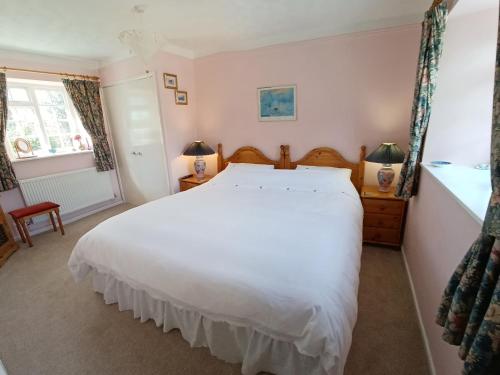 a bedroom with a large white bed and a window at Magpie Cottage in South Brewham