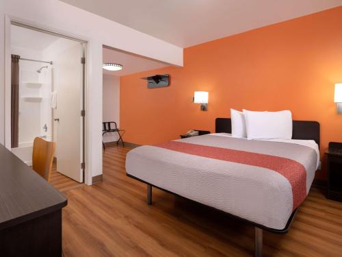 a hotel room with a large bed with orange walls at Motel 6-Santa Maria, CA - North in Santa Maria