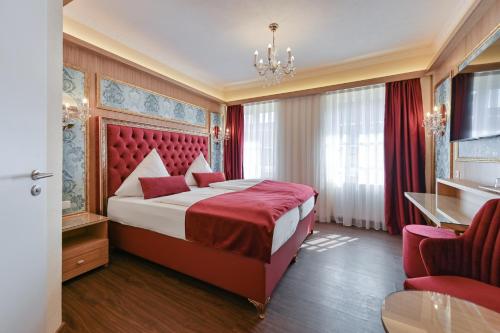 Schlafzimmer mit einem großen Bett und einem roten Kopfteil in der Unterkunft Hotel Ludwigs in Füssen