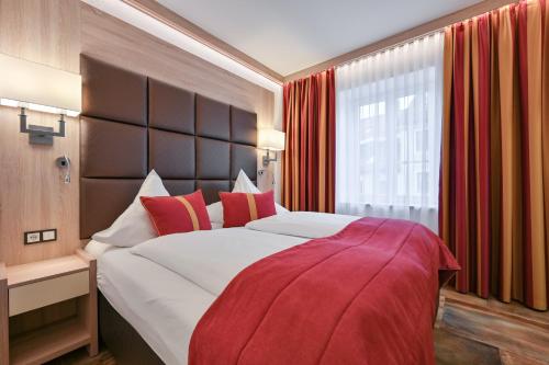 a bedroom with a large bed with red pillows at Hotel Ludwigs in Füssen