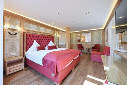 a bedroom with a large bed with a red headboard at Hotel Ludwigs in Füssen