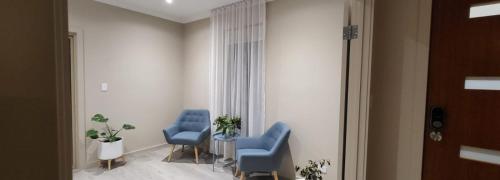 a room with two blue chairs and a table at Newly built cozy double storey 3 bed room house at Prospect. in Prospect