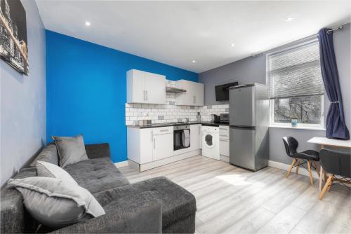 a living room with a couch and a blue wall at Stockton town centre studio apartments free parking and Wi-Fi in Stockton-on-Tees