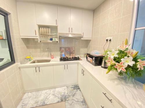 a kitchen with white cabinets and a vase of flowers at EasyOne Homestay@Vista Bangi in Kajang