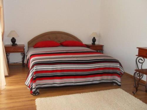 a bedroom with a bed with a striped blanket on it at Guest House del Mare in Dobra Voda