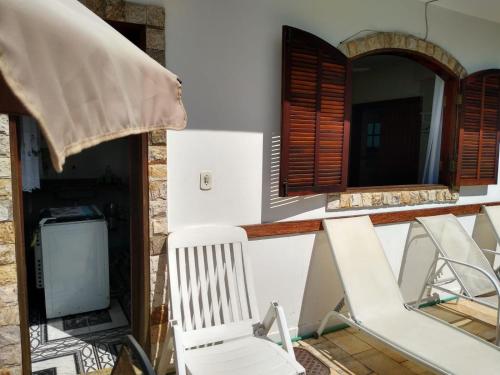 eine Veranda mit einem weißen Stuhl und einem Spiegel in der Unterkunft Cabo Frio Suíte com cozinha in Cabo Frio