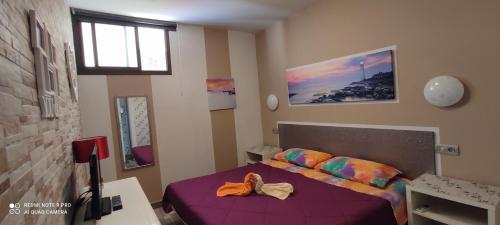 una camera da letto con un letto viola con un fiocco sopra di MGT - Appartamento sulla Spiaggia con terrazza romantica a Puerto Rico de Gran Canaria