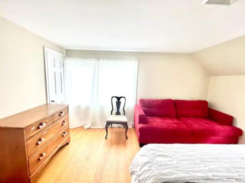a bedroom with a red couch and a dresser at Town Plot Waterbury in Waterbury
