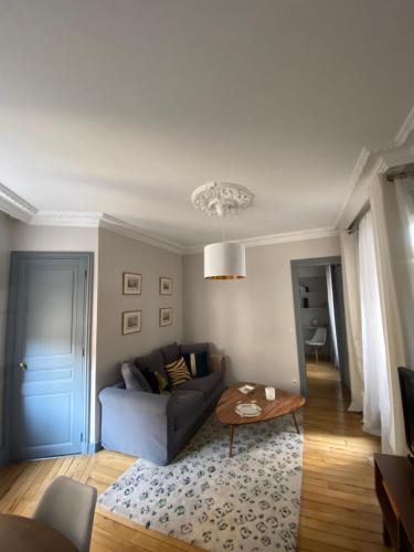 een woonkamer met een bank en een tafel bij Elegant appartement Trocadéro in Parijs