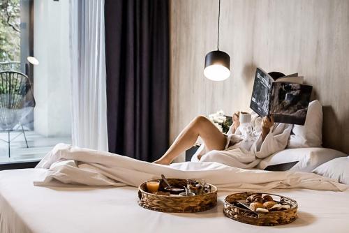 Una donna seduta su un letto che legge un libro di Krista Boutique Hotel a Buenos Aires