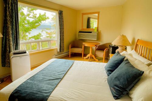 a bedroom with a large bed with a large window at Glenghorm Beach Resort in Ingonish