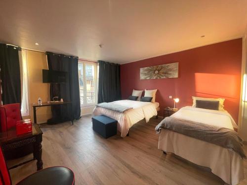 - 2 lits dans une chambre aux murs rouges dans l'établissement Leclerc Hotel Centre Gare, au Mans