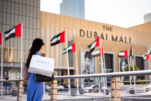 a woman standing in front of a building with flags at Unlock Metropolis Business Bay in Dubai