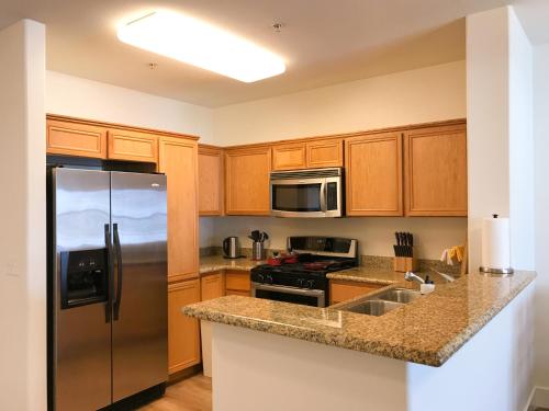a kitchen with wooden cabinets and a stainless steel refrigerator at Perfect Apt near UCLA w Parking Gym Pool WIFI in Westwood B3 in Los Angeles