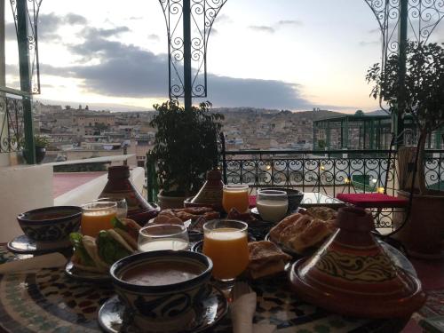a table with a plate of food and orange juice at Riad Taj Salma in Fès
