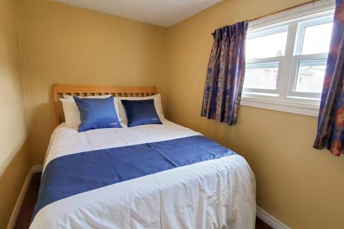 a bedroom with a bed with blue pillows and a window at Glenghorm Beach Resort in Ingonish