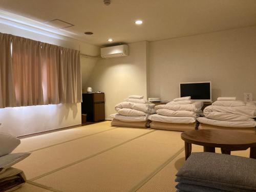 a room with a pile of white towels at J-Hoppers Beppu Guesthouse ジェイホッパーズ別府ゲストハウス in Beppu