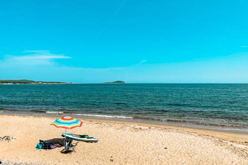 a beach with an umbrella and a surfboard on the beach at Glenghorm Beach Resort in Ingonish