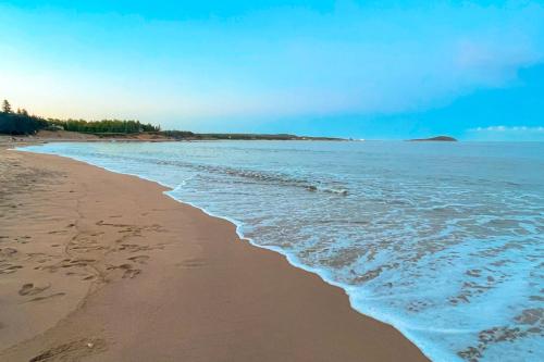 a beach with footprints in the sand and the ocean at Glenghorm Beach Resort in Ingonish