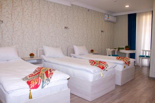 um quarto com três camas num quarto em Hotel Taht em Tashkent